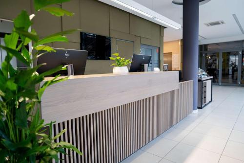 an office lobby with a reception counter with plants at Lanzcarré Hotel Mannheim, a member of Radisson Individuals in Mannheim