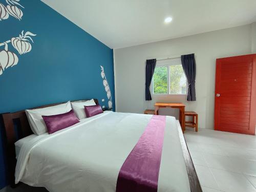 1 dormitorio con 1 cama blanca grande con almohadas moradas en Be Leaf Resort SHA, en Thalang