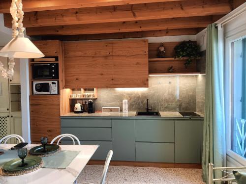 una cocina con armarios de madera y una mesa con sillas. en Suite Latina - San Leonardo, en Treviso