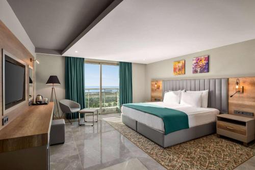 um quarto de hotel com uma cama e uma televisão em Ramada Resort By Wyndham Kizkalesi em Kizkalesi