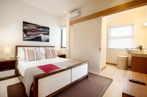 a bedroom with a large bed and a sink at Cap Ouest Luxury Beachfront in Flic-en-Flac