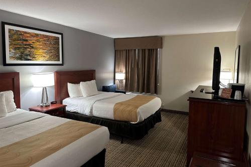 a hotel room with two beds and a television at Baymont by Wyndham South Bend Near Notre Dame in South Bend