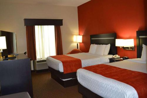 una camera d'albergo con due letti e pareti rosse di Days Inn by Wyndham Laurel MS a Laurel