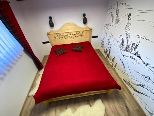 a bedroom with a bed with a red blanket at Domek Góralski na Ubocy z jacuzzi in Białka Tatrzanska