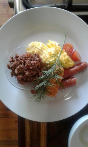 a plate of food with eggs sausage and vegetables at Sevens Guesthouse in Kroonstad