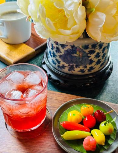 a drink and a plate of vegetables and a vase with flowers at neil niwas in Bangkok