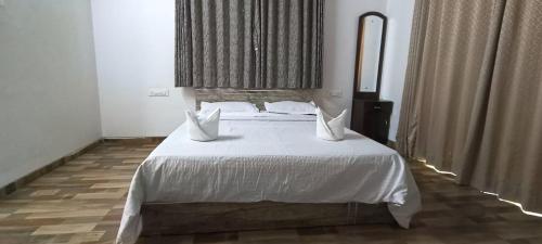 a bedroom with a large bed with white sheets and pillows at Rain Forest Resort in Lonavala