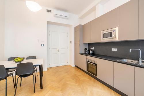 a kitchen with white cabinets and a table and chairs at Petrin Tower Residence in Prague