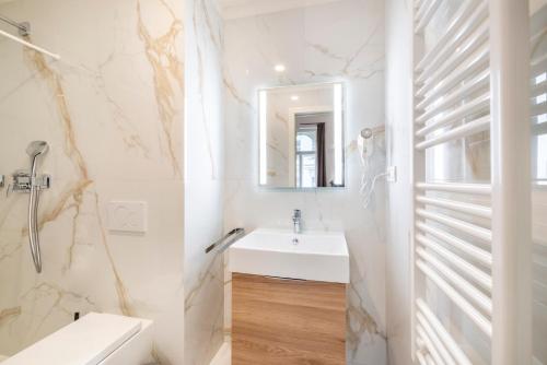 a white bathroom with a sink and a mirror at Petrin Tower Residence in Prague