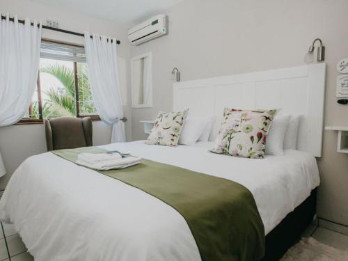 ein Schlafzimmer mit einem großen weißen Bett und einem Fenster in der Unterkunft Sylvern Bed and Breakfast in Durban