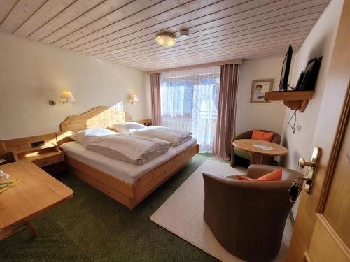 Hotel Obergfell في تودتناو: غرفة نوم بسرير وطاولة وكرسي