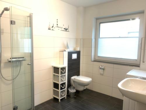 ein Bad mit einem WC, einem Waschbecken und einer Dusche in der Unterkunft Backbord in Horumersiel