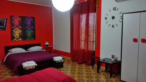 a red bedroom with a bed and a clock on the wall at B&B Colors in Sellia Marina