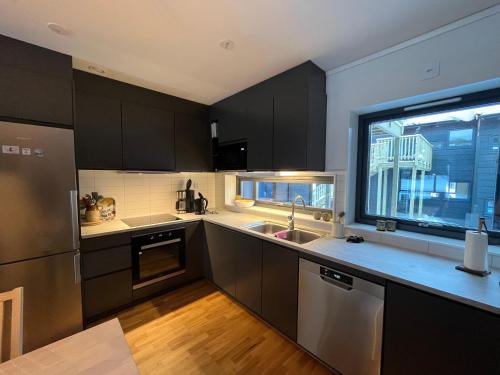 a kitchen with black cabinets and a large window at Funäs Fjällby Funäsdalen in Funäsdalen