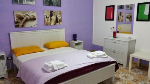 a bedroom with purple walls and a bed with yellow pillows at B&B Colors in Sellia Marina