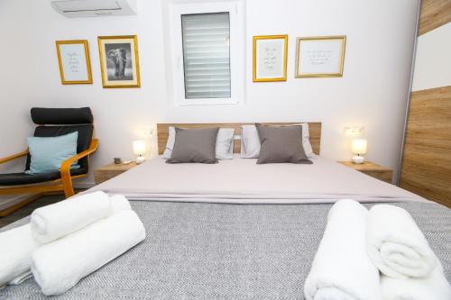 a bedroom with a large bed and a chair at Holiday home Ambi for 6, heated pool near Trogir in Trogir