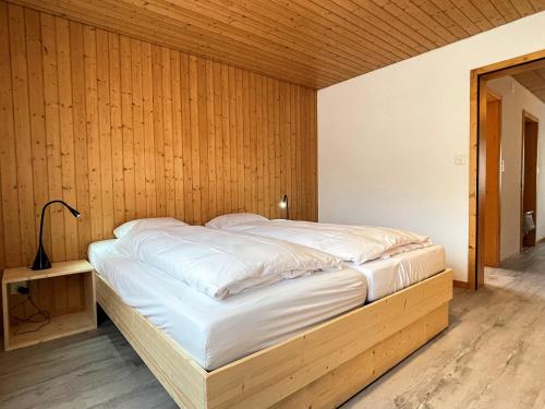 a large bed in a room with wooden walls at Carpe Diem in Wildhaus