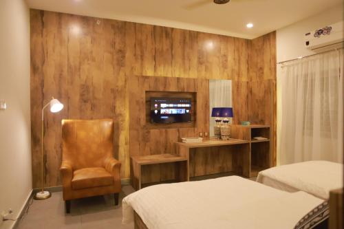 a hotel room with two beds and a chair at Sunset BnB in Karachi
