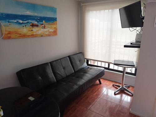 sala de estar con sofá negro y mesa en Cabañas Mediterraneas, en Pichidangui