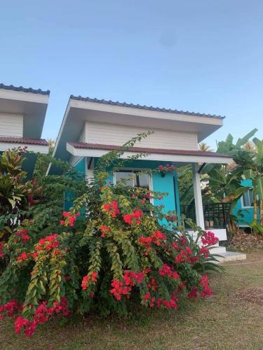 a house with red flowers in front of it at Baan Kebsap บ้านเก็บทรัพย์ in Ko Yao Noi