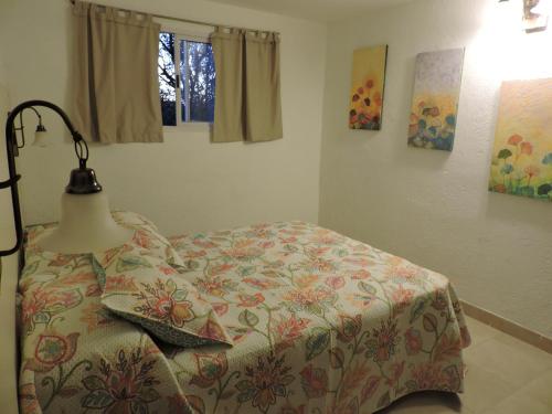 1 dormitorio con 1 cama con manta de flores y lámpara en Cabañas La Comarca en Merlo