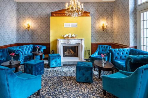 a waiting room with blue chairs and a fireplace at Seehotel Schloss Klink in Klink