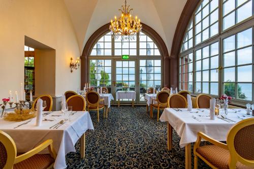 a dining room with tables and chairs and a chandelier at Seehotel Schloss Klink in Klink
