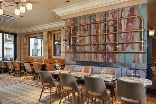 a dining room with tables and chairs and a wall with a mural at Le Robinet d'Or in Paris