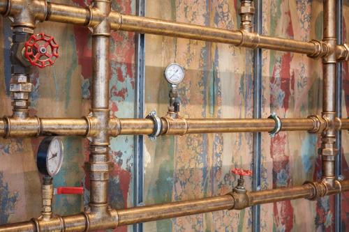 a bunch of pipes are on a wall at Le Robinet d'Or Paris Canal Saint Martin in Paris