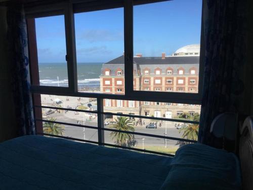 ventana del dormitorio con cama y vistas a un edificio en Departamento frente al mar con increible vista, a metros del casino en Mar del Plata