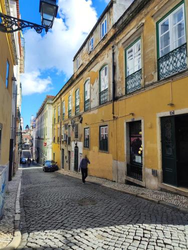 a person walking down a cobblestone street next to buildings at Guest House Rooms in Bairro Alto in Lisbon