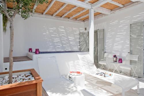 Habitación blanca con mesa y árbol en Grace Mykonos, en Agios Stefanos