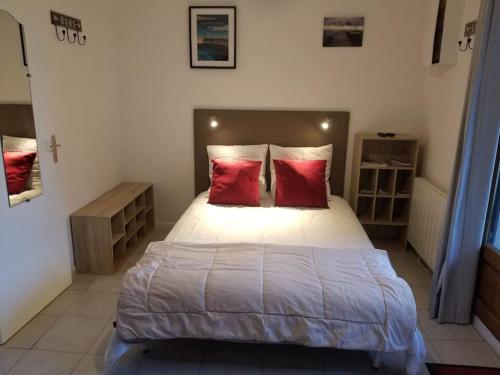 une chambre avec un grand lit avec deux oreillers rouges dans l'établissement Studio de plain-pied avec terrasse tout proche mer, à Courseulles-sur-Mer