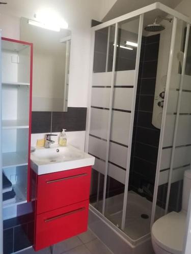 La salle de bains est pourvue d'un lavabo rouge et d'une douche. dans l'établissement Studio de plain-pied avec terrasse tout proche mer, à Courseulles-sur-Mer