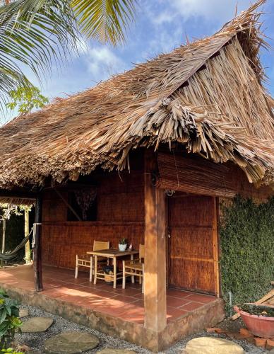 ベンチェにあるPhuc Sinh Homestayの茅葺き屋根の小屋(テーブル付)