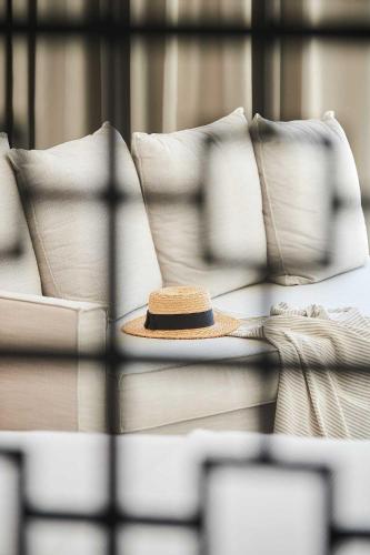 a hat sitting on a couch with pillows at Cavo Delea Villas & Suites in Possidi