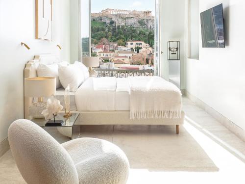 a bedroom with a bed and a chair and a window at The Dolli at Acropolis, A Hotel to Live in Athens
