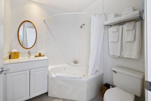 a white bathroom with a tub and a toilet and a sink at Pier View Suites - Studio A in Cayucos