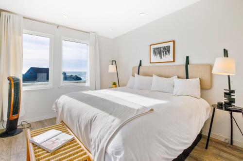 a bedroom with a large white bed with a window at Pier View Suites - Studio A in Cayucos