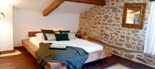 - une chambre avec un mur en pierre et un lit dans l'établissement Maison familiale chaleureuse idéalement située, à Silhac