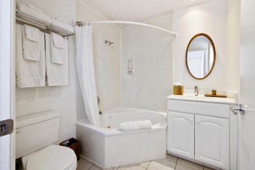baño blanco con bañera, aseo y lavamanos en Pier View Suites - Studio B, en Cayucos