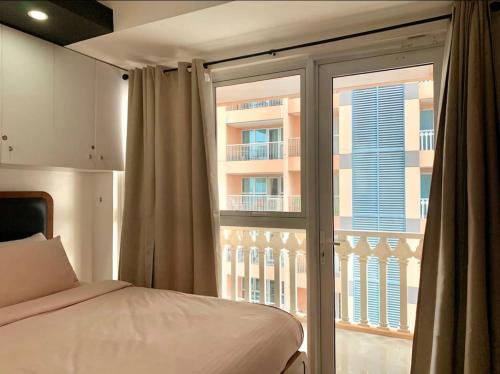 - une chambre avec un lit et une grande fenêtre dans l'établissement Luxury 1BR Unit with Pool at Venice Luxury Residences, Tower Domenico, McKinley Hill, Taguig City, à Manille