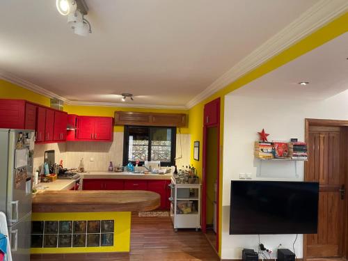 a kitchen with red and yellow cabinets and a flat screen tv at Chambre diambar in Saly Portudal
