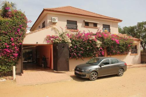 a car parked in front of a house with flowers at Chambre diambar in Saly Portudal