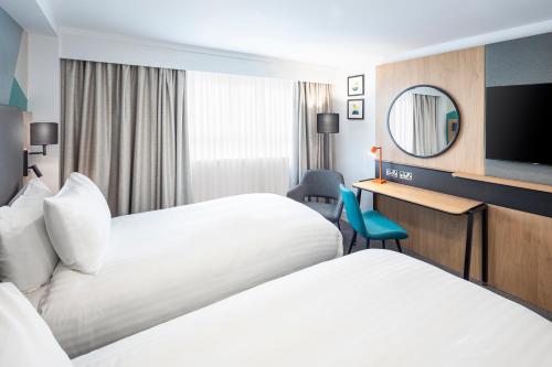 a hotel room with two beds and a mirror at Holiday Inn Southampton Eastleigh by IHG in Southampton