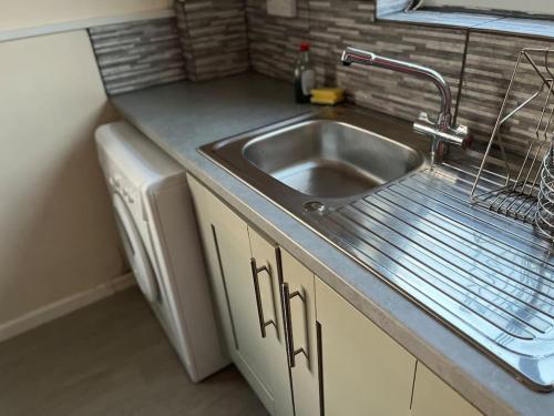 a kitchen counter with a sink and a dishwasher at The glorious 3 bedroom apartment with parking in Nottingham