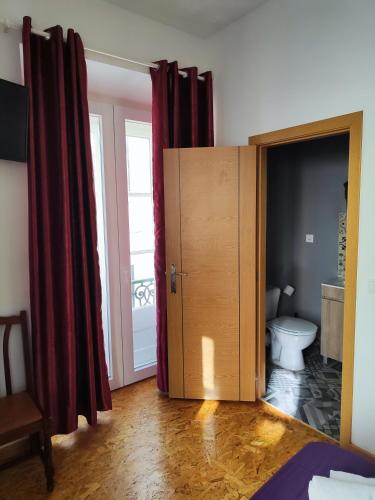 a bathroom with a toilet in a room with red curtains at Guest House Rooms in Bairro Alto in Lisbon