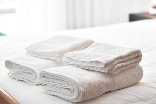 a pile of white towels sitting on top of a bed at Lido Gardens Funchal in Funchal