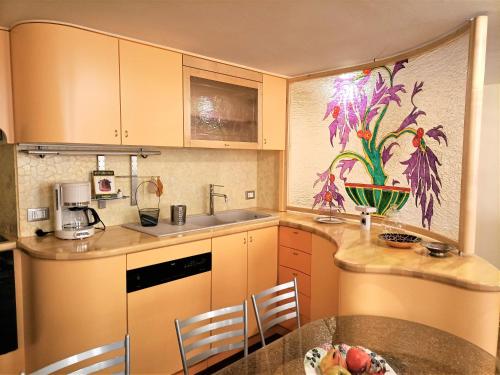 een keuken met gele kasten en een tafel met een fruitschaal bij Casa Alexandra in centro e a pochi passi dal mare in Imperia