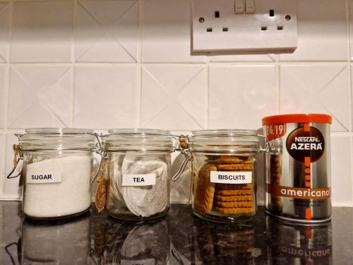 a counter with four jars of food on it at Stylish Luxury Serviced Apartment next to City Centre with Free Parking - Contractors & Relocators in Coventry